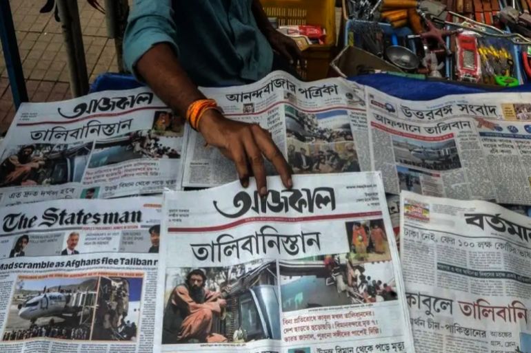 A newspaper vendor sells and arranges newspapers displaying front page news about Afghanistan at roadside stall in Siliguri on August 17, 2021. featuring the front page news of conflicts in Afghanistan in Siliguri on August 17, 2021 after the Taliban's stunning military takeover of Afghanistan. (Photo by Diptendu DUTTA / AFP) (Photo by DIPTENDU DUTTA/AFP via Getty Images)
