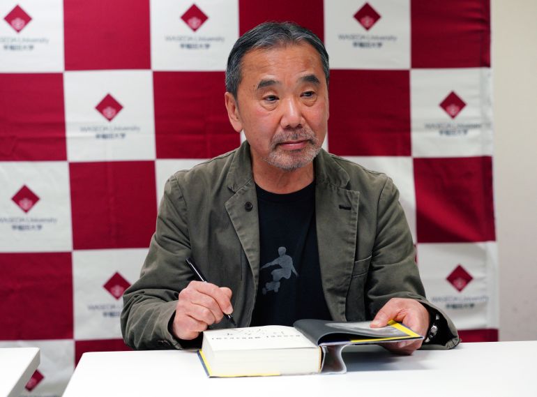 Japanese novelist Haruki Murakami signs his autograph on his novel