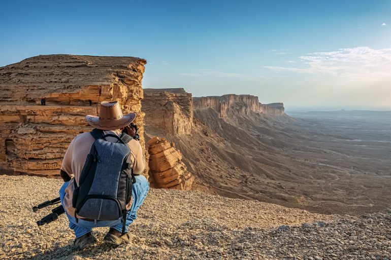 An adventure photographer in Edge of the World, a natural landmark and popular tourist destination near Riyadh -Saudi Arabia.; Shutterstock ID 1707058168; purchase_order: aj; job: ; client: ; other: