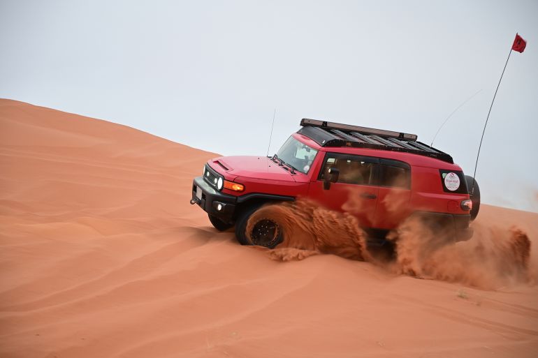 4x4 cars drift across Saudi Arabia’s striking red sand desert. The vehicles perform thrilling maneuvers, sending sand flying in dramatic arcs against the backdrop of the vast vibrant dunes near Riyadh; Shutterstock ID 2494509707; purchase_order: aj; job: ; client: ; other: