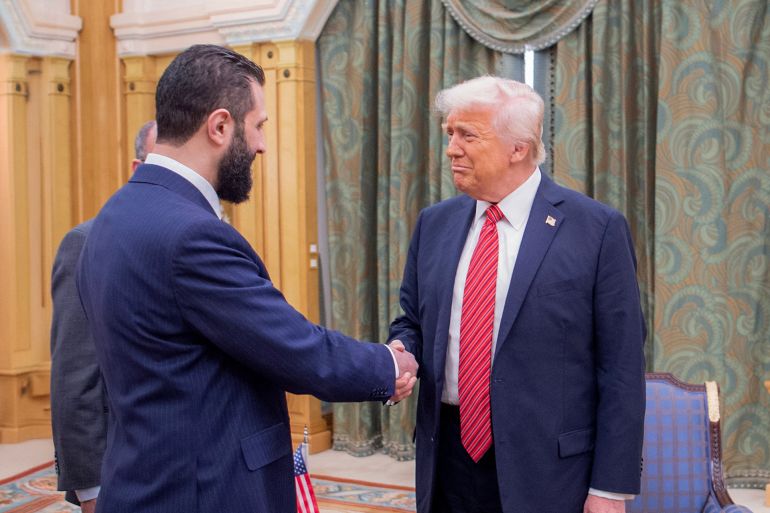 A handout picture provided by the Saudi Royal Palace shows US President Donald Trump (C) shakes hands with Syria's interim president Ahmed al-Sharaa in Riyadh on May 14, 2025. Trump became the first US president in 25 years to meet a Syrian leader on May 14, after he offered sanctions relief in hopes of offering a new path to the war-battered country. (Photo by Bandar AL-JALOUD / Saudi Royal Palace / AFP) / RESTRICTED TO EDITORIAL USE - MANDATORY CREDIT