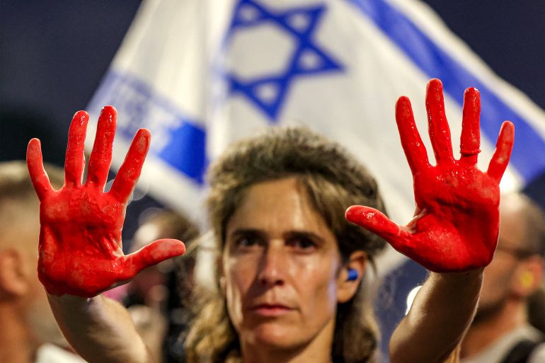 A demonstrator displays her hands painted in red to depict blood during an anti-government protest calling for action to secure the release of Israeli hostages held captive in the Gaza Strip by Palestinian militants since the 2023 October 7 attacks, outside the Israeli Defence Ministry headquarters in Tel Aviv on August 2, 2025. (Photo by Jack GUEZ / AFP)