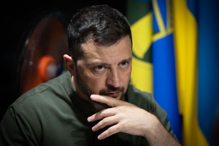In this handout photograph taken and released by the Ukrainian Presidential Press Service on August 4, 2025, Ukraine's President Volodymyr Zelensky looks on as he meets with soldiers of the 57th Separate Motorised Infantry Brigade on the frontline positions at an undisclosed location in the Kharkiv region, amid the Russian invasion of Ukraine.