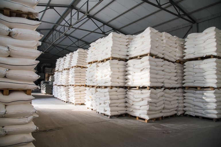 Food warehouse. Bags of rice, sugar, flour and other products. Warehouse filled with white heavy bags that lie on pallets
