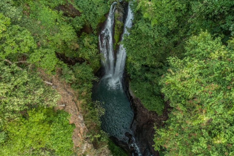 Jungle waterfall cascade in tropical rainforest with rock and turquoise blue pond. Its name Banyumala because its twin waterfall in mountain slope; Shutterstock ID 1015564531; purchase_order: ajnet; job: ; client: ; other: بالي